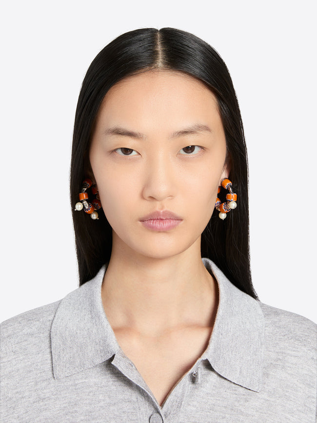 Woman wearing earrings with a plain background - Dries Van Noten