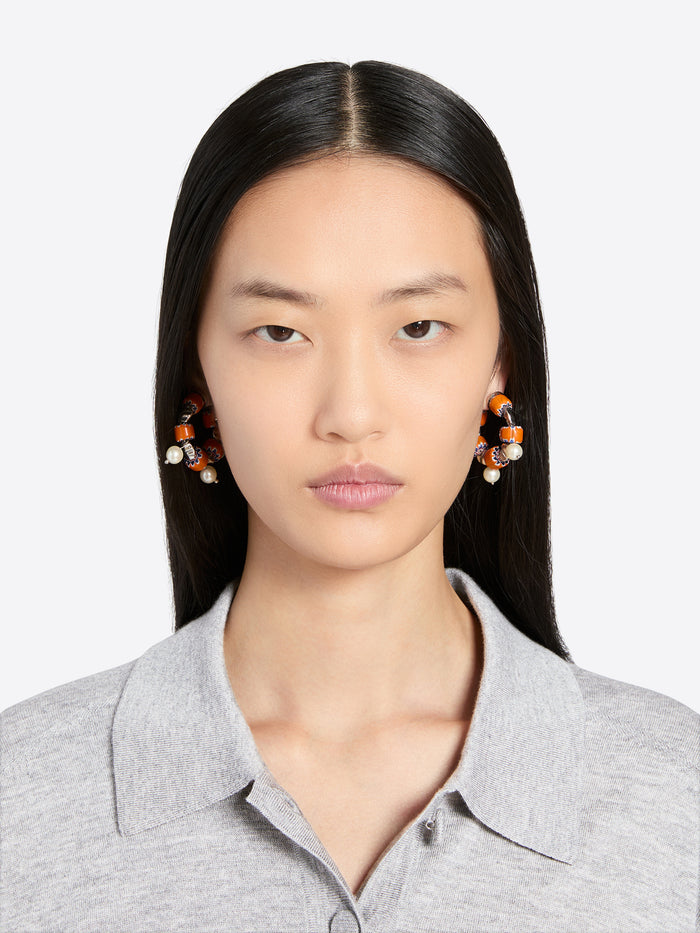 Woman wearing earrings with a plain background - Dries Van Noten