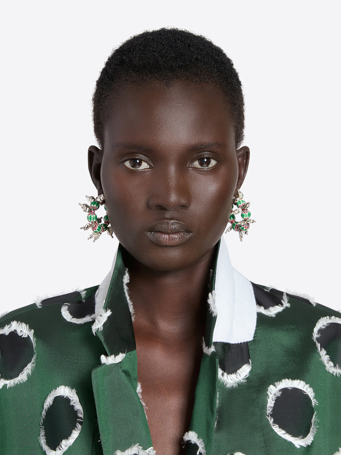 Woman wearing a green patterned outfit with large earrings on a white background - Dries Van Noten