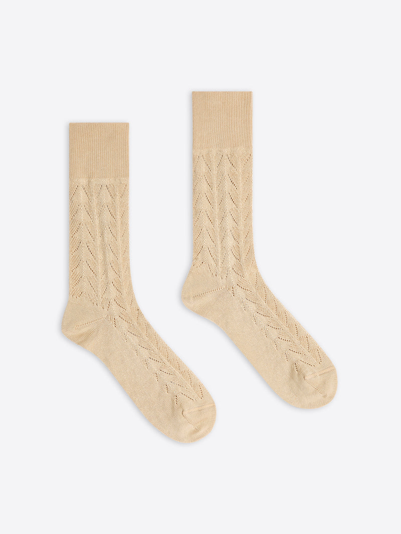 Pair of beige cable-knit socks on a white background
