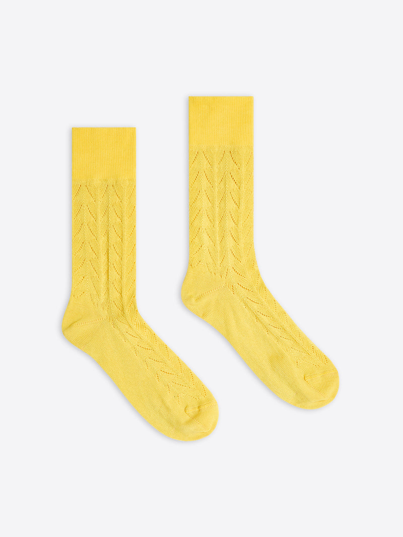 Pair of yellow knee-high socks with cable knit pattern on a white background