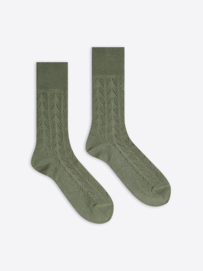 Pair of green socks with cable knit pattern on a white background