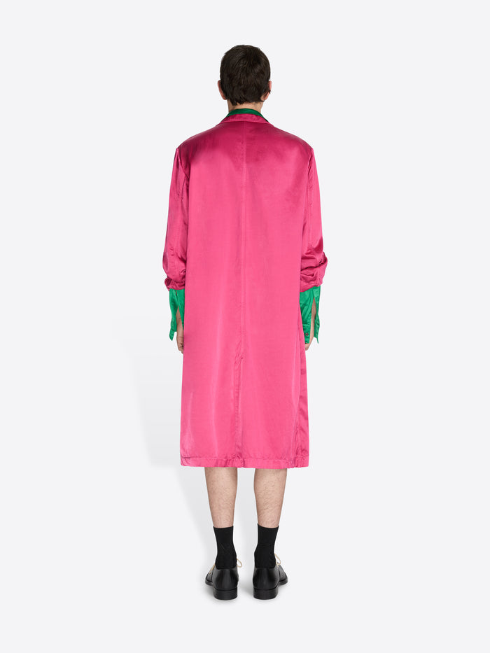 Person wearing a bright pink coat with green accents on a white background