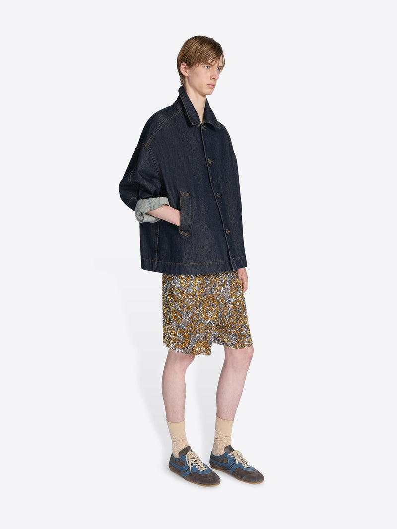 Person wearing a dark jacket, patterned shorts, and sneakers on a white background - Dries Van Noten