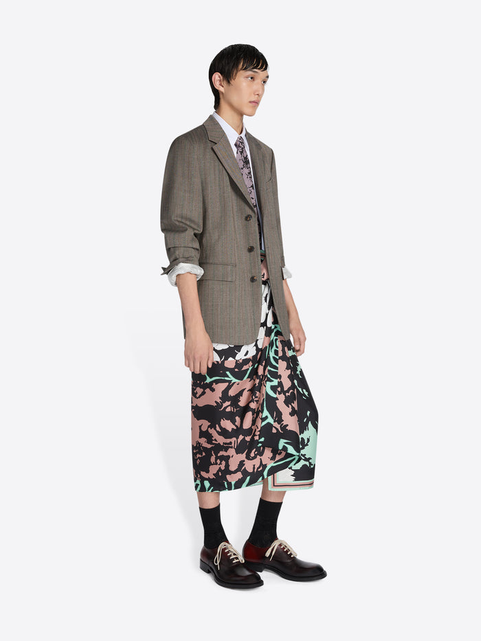 Person wearing a long coat over a floral dress with a white background