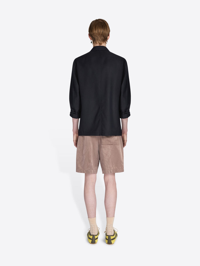 Person wearing a black shirt and beige shorts on a white background