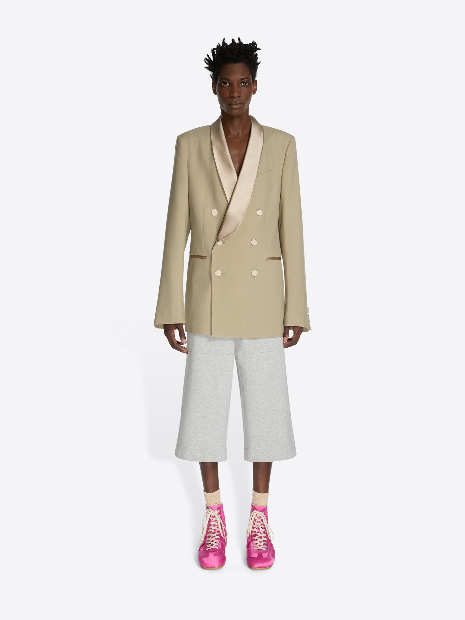 Person wearing a beige blazer, white pants, and pink shoes on a white background - Dries Van Noten