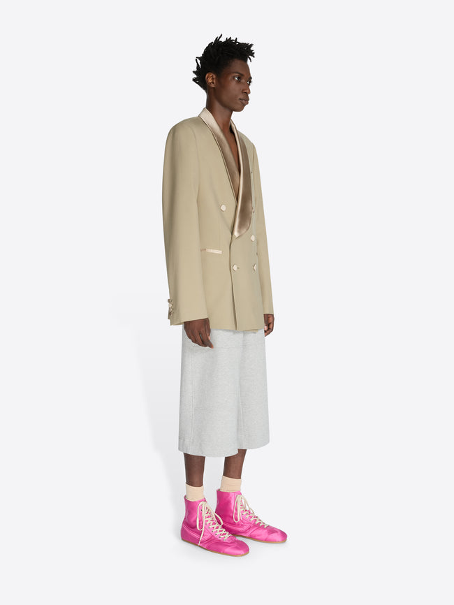 Person wearing a beige blazer, white pants, and pink shoes on a white background - Dries Van Noten