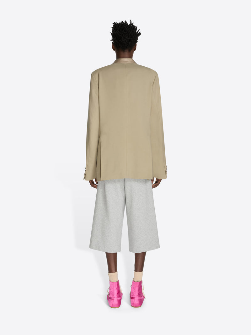 Person wearing a beige coat, light gray pants, and pink shoes on a white background - Dries Van Noten