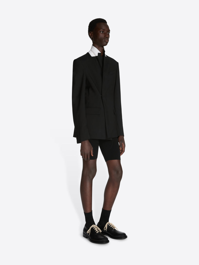 Person wearing a black suit with a white shirt on a white background - Dries Van Noten
