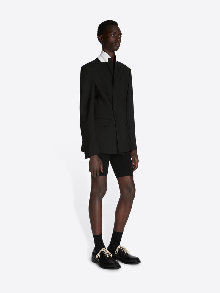 Person wearing a black suit with a white shirt on a white background - Dries Van Noten