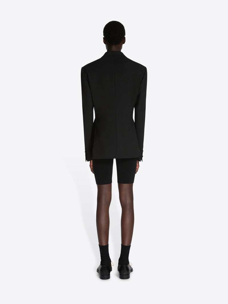 Person wearing a black blazer and black shorts on a white background - Dries Van Noten