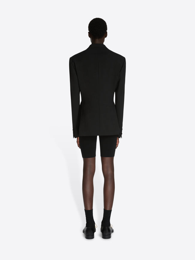 Person wearing a black blazer and black shorts on a white background - Dries Van Noten