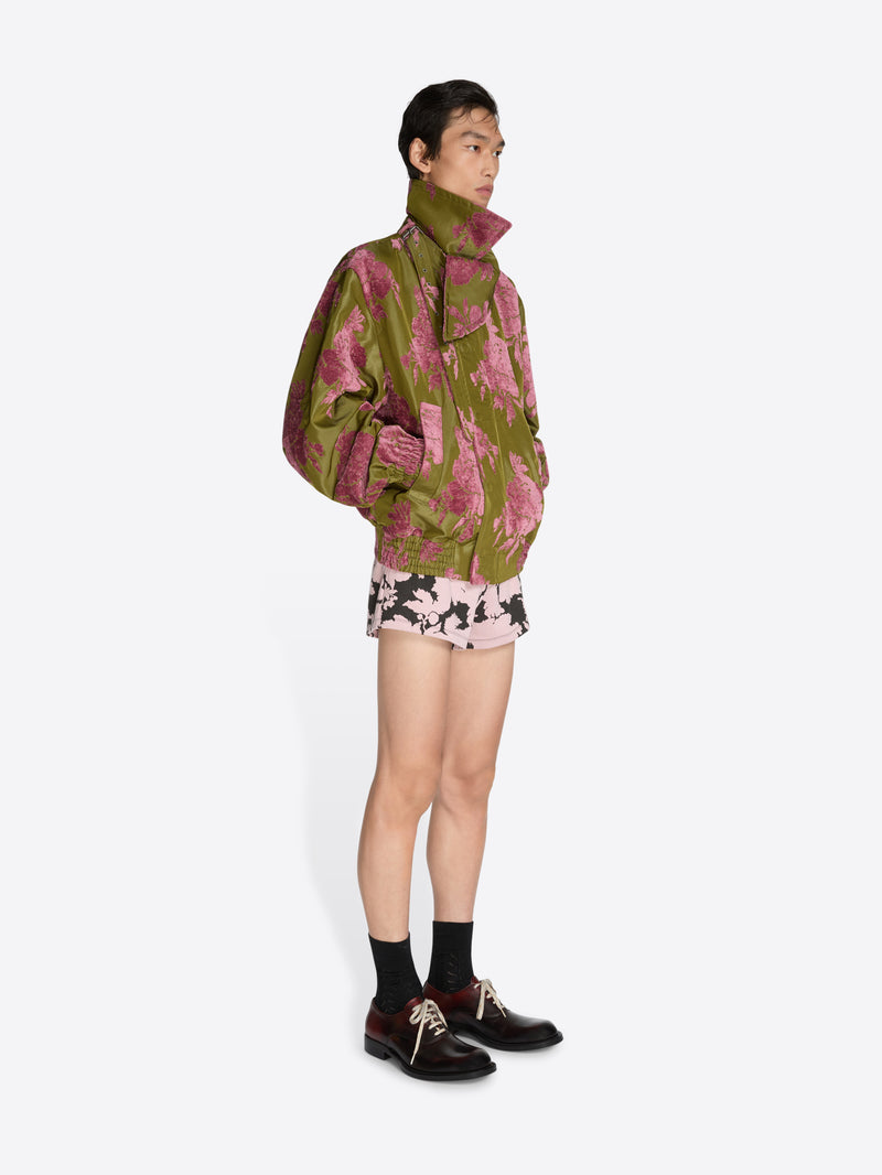 Person wearing a patterned jacket and shorts on a white background