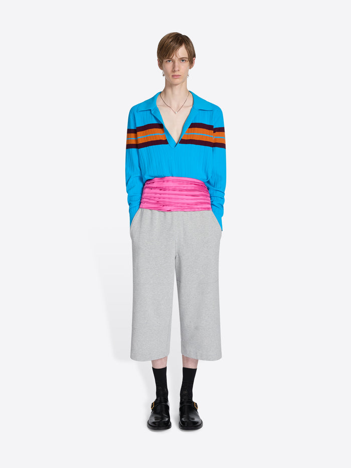 Person wearing a colorful striped shirt and gray pants on a white background - Dries Van Noten
