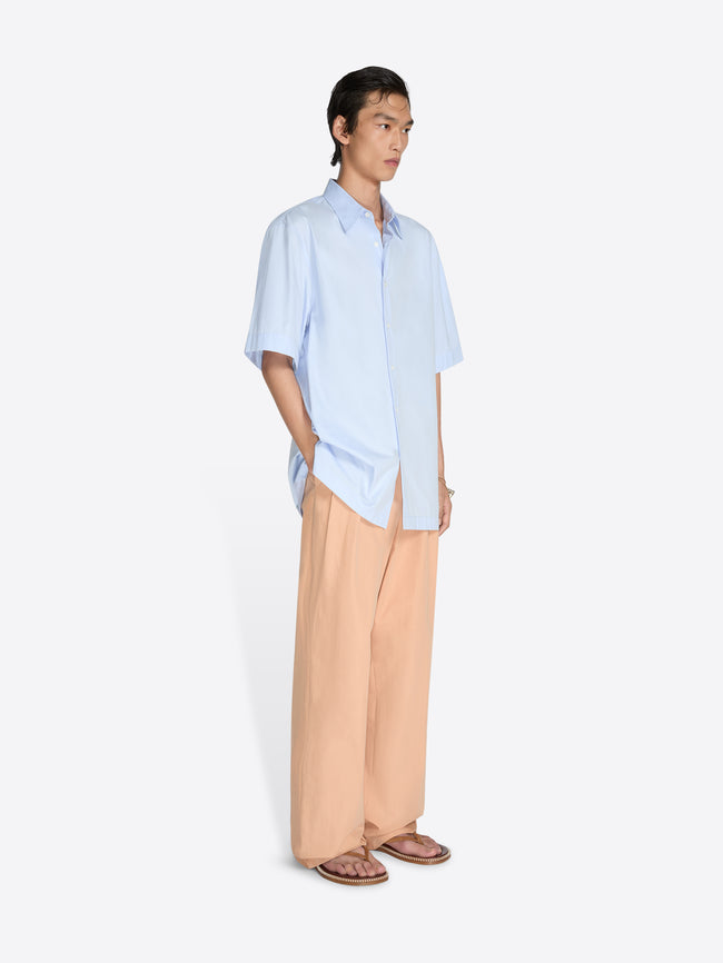 Person wearing a light blue shirt and beige pants on a white background