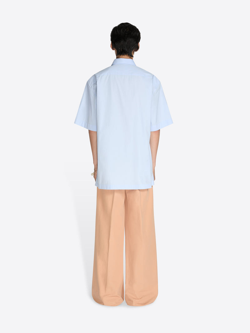 Person wearing a light blue shirt and beige pants on a white background