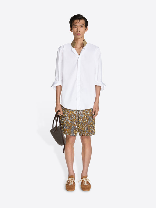 Person wearing a white shirt and patterned shorts on a white background