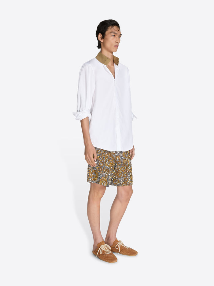 Person wearing a white shirt and patterned shorts on a white background