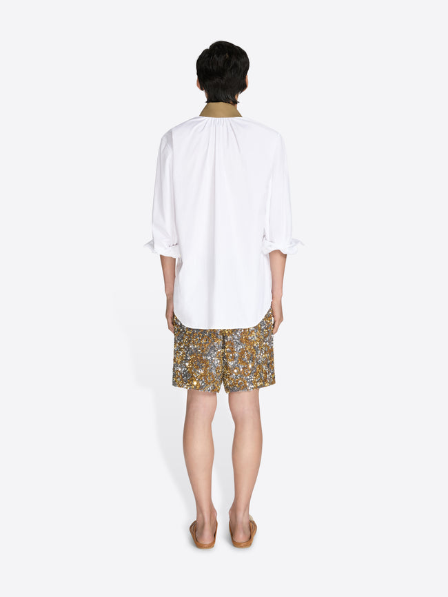 Person wearing a white blouse and patterned shorts on a white background