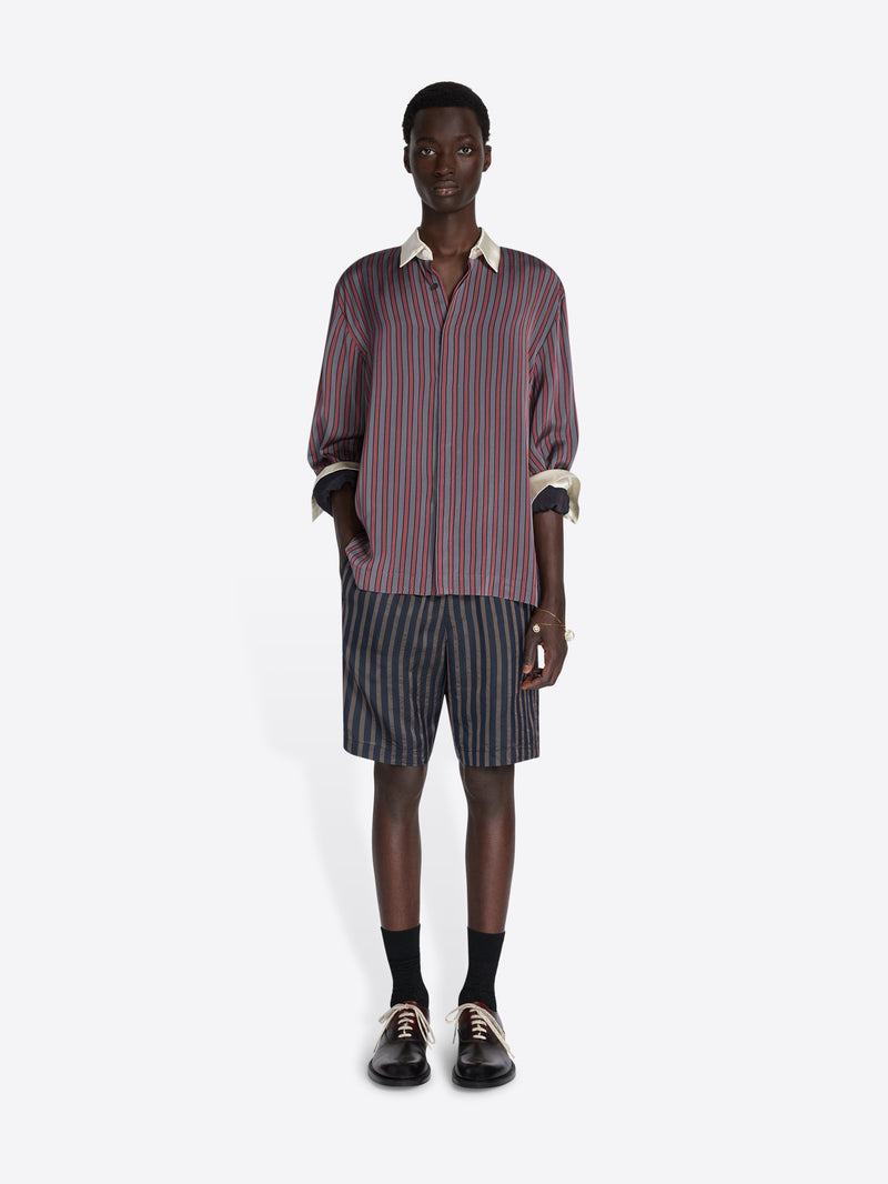 Person wearing a striped shirt and shorts on a white background