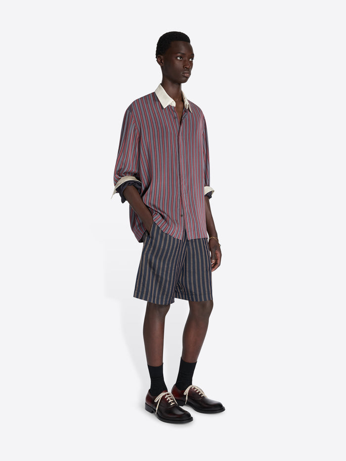 Man wearing a striped shirt and shorts on a white background