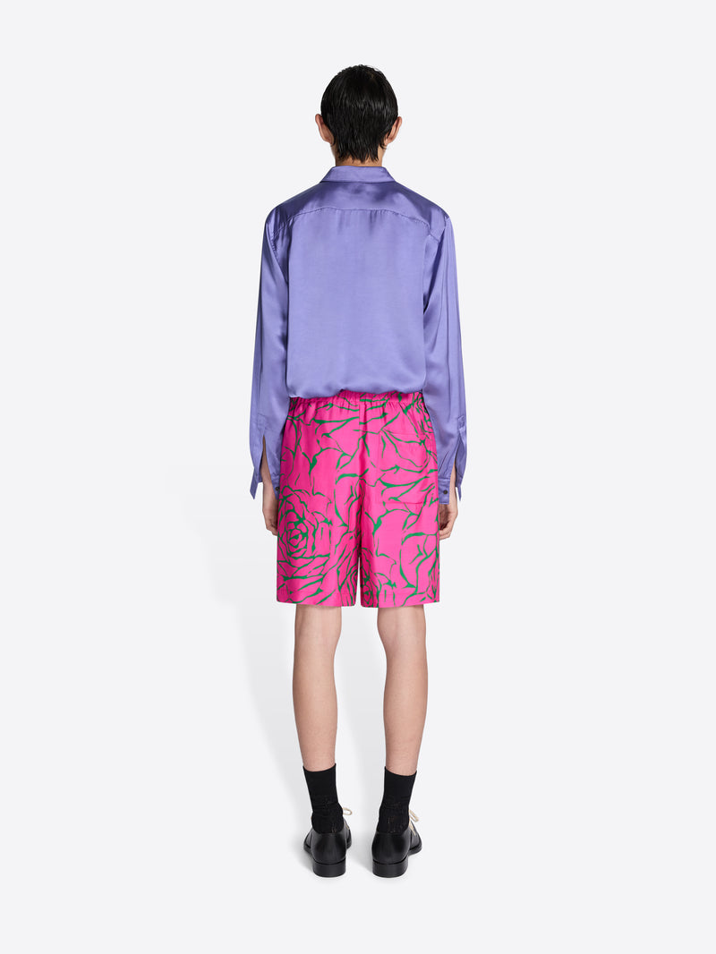 Person wearing a purple shirt and pink shorts with a leaf pattern on a white background