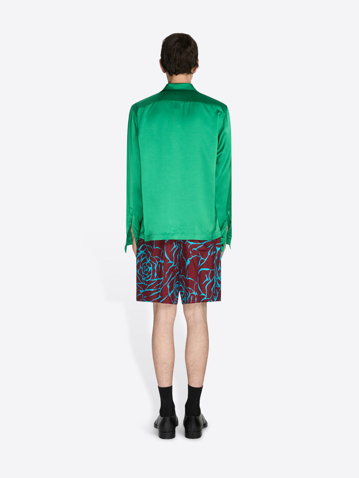 Person wearing a green shirt and patterned shorts on a white background