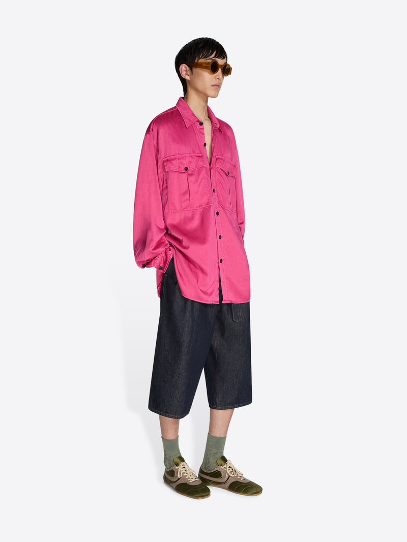 Person wearing a bright pink shirt and black shorts on a white background - Dries Van Noten