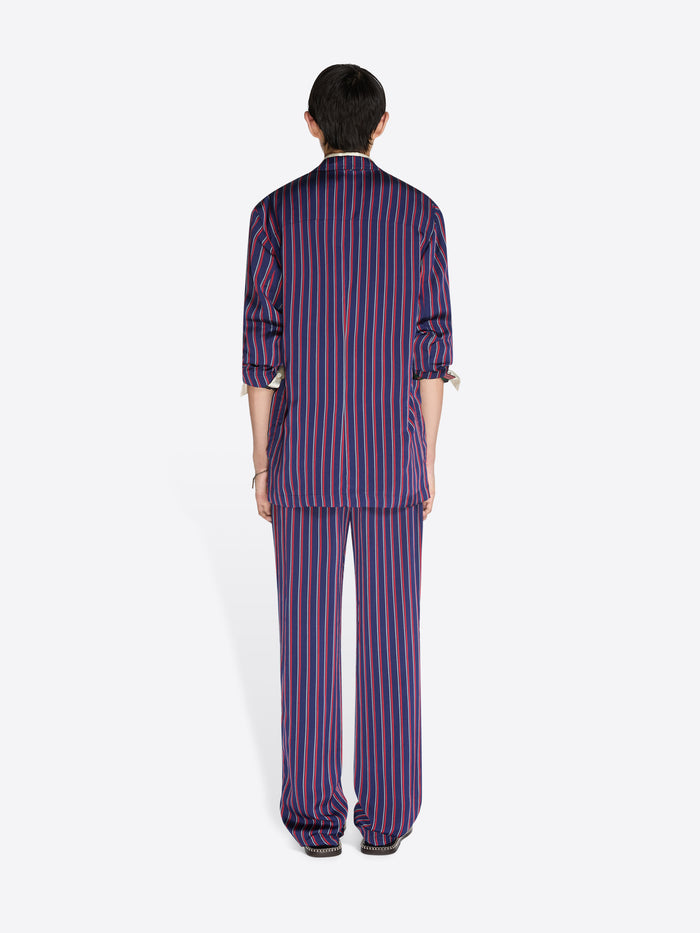 Person wearing a purple and red striped pajama set on a white background - Dries Van Noten