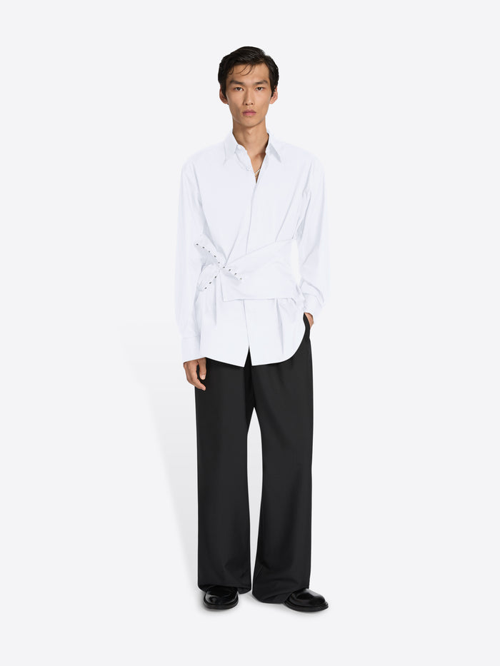 Person wearing a white shirt and black pants on a white background