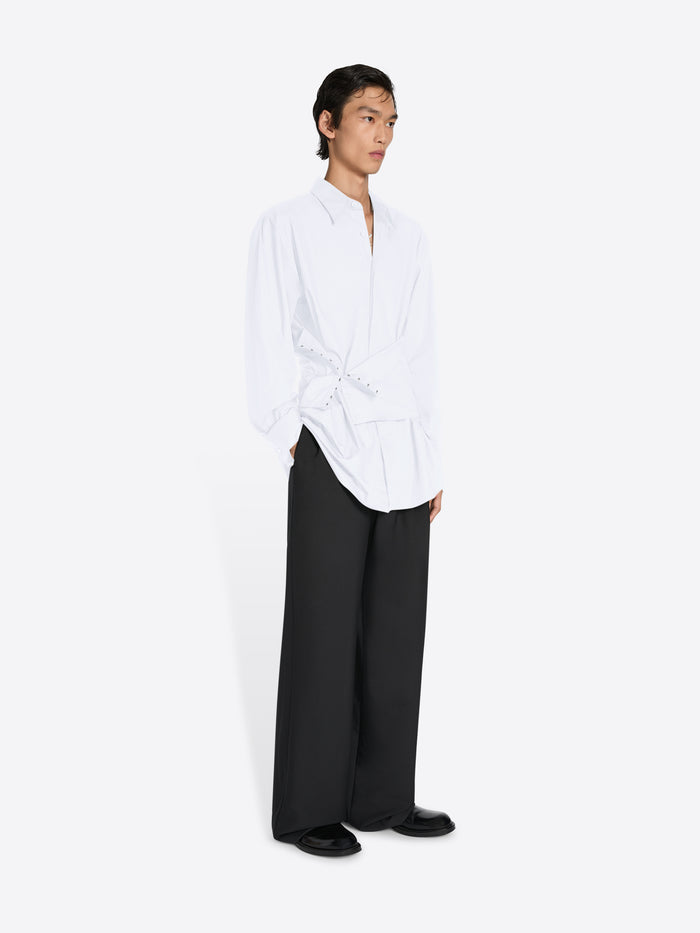 Person wearing a white shirt and black pants on a white background