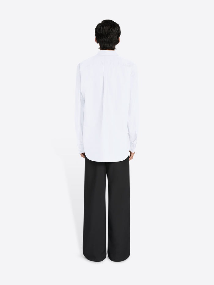 Person wearing a white shirt and black pants on a white background