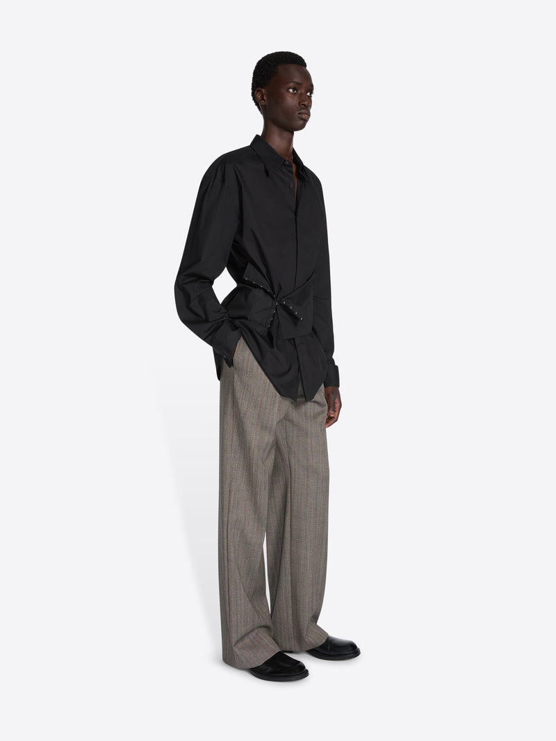 Person wearing a black shirt and gray pants on a white background