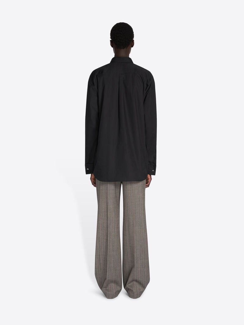 Person wearing a black coat and gray pants on a white background