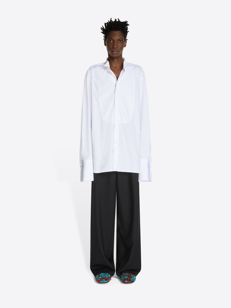 Person wearing a white shirt and black pants on a white background
