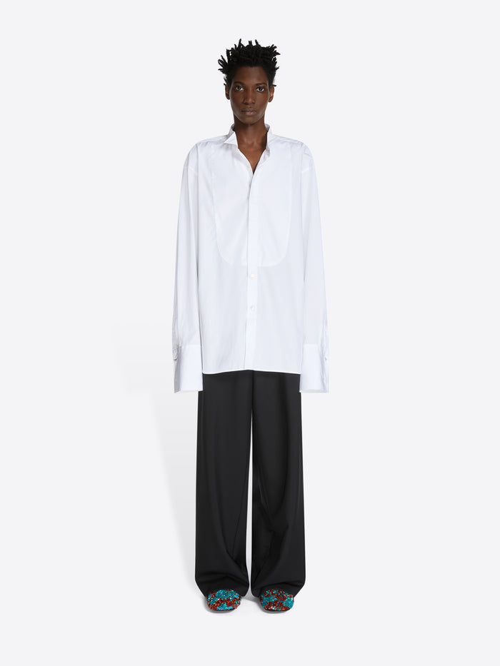 Person wearing a white shirt and black pants on a white background