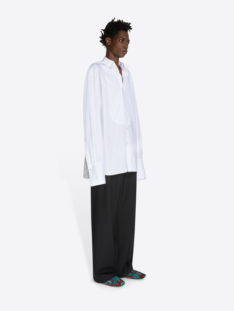 Person wearing a white shirt and black pants on a white background