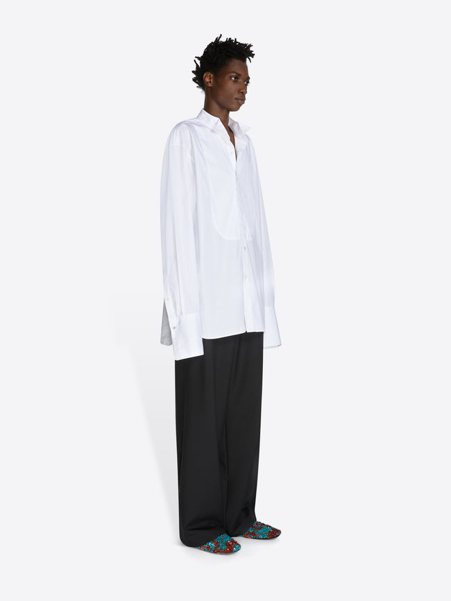 Person wearing a white shirt and black pants on a white background