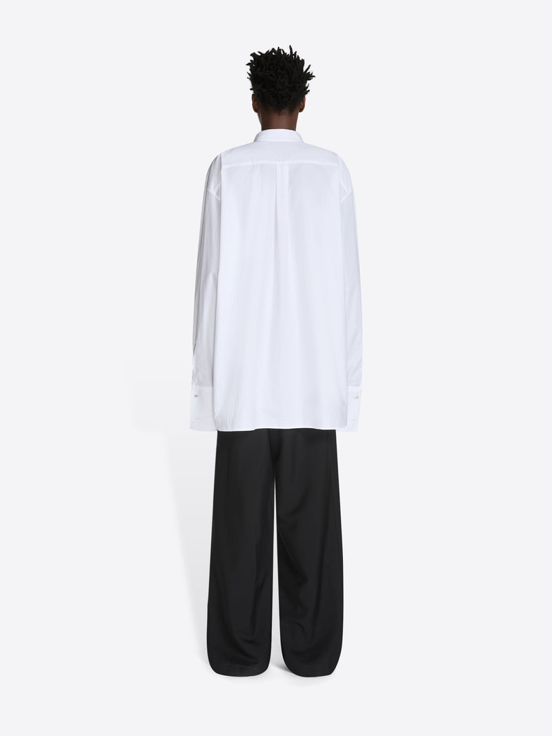 Person wearing a white shirt and black pants on a white background