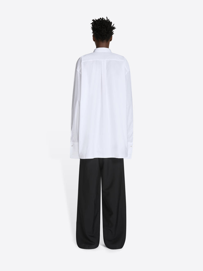 Person wearing a white shirt and black pants on a white background