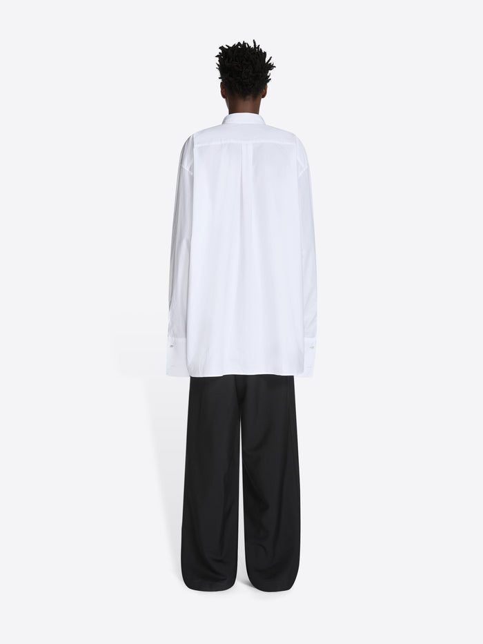 Person wearing a white shirt and black pants on a white background