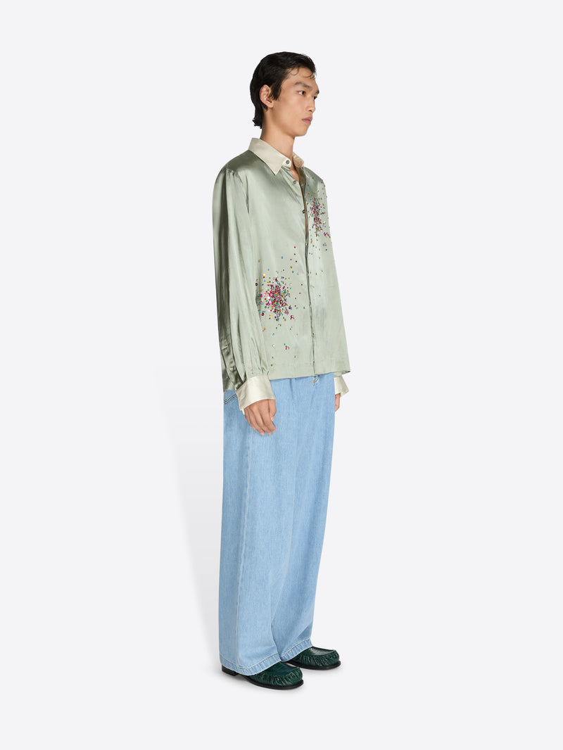 Person wearing a light green embroidered shirt and light blue pants on a white background - Dries Van Noten