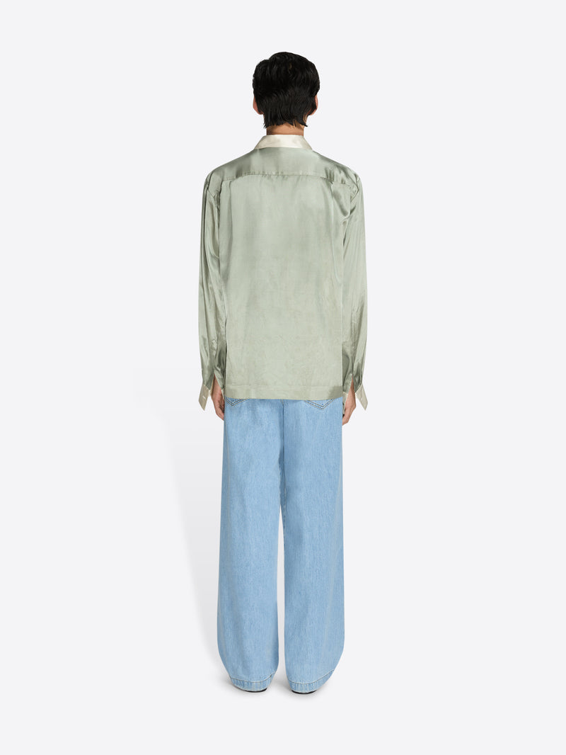 Person wearing a light green shirt and light blue jeans on a white background - Dries Van Noten