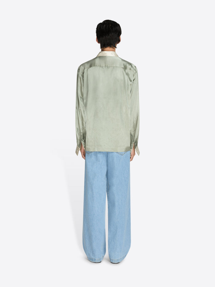 Person wearing a light green shirt and light blue jeans on a white background - Dries Van Noten