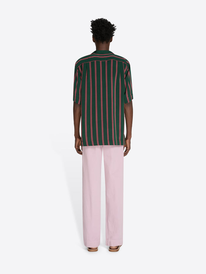Person wearing a green and red striped shirt with pink pants on a white background