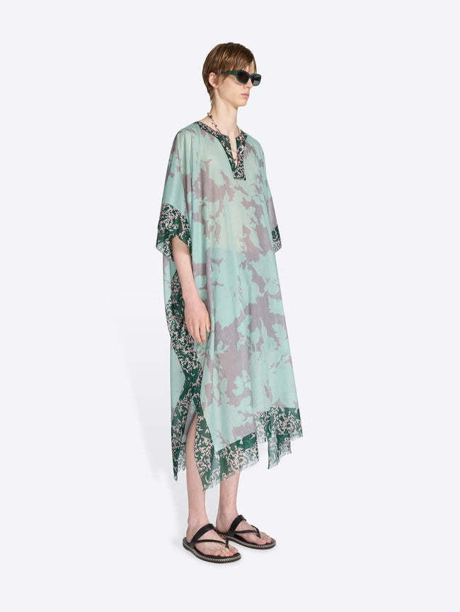 Μan wearing a light green floral dress on a white background