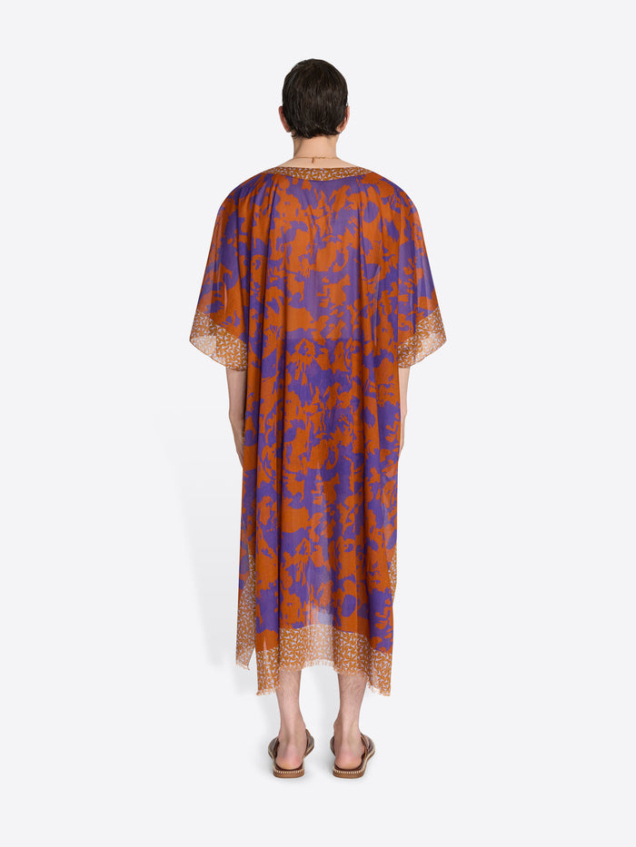 Man wearing a patterned orange and blue dress on a white background