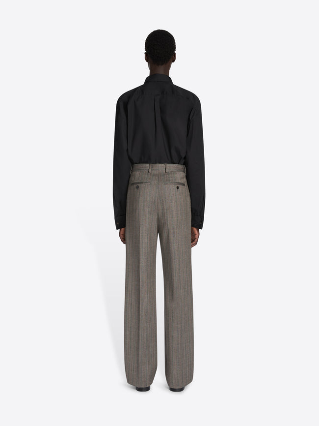 Person wearing a black shirt and gray pants on a white background