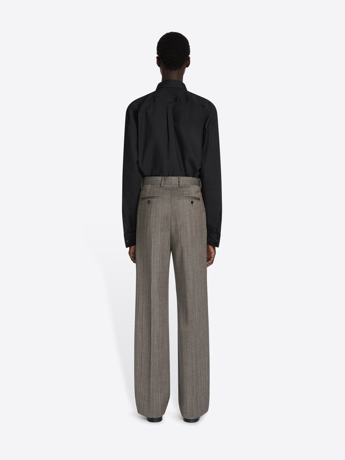 Person wearing a black shirt and gray pants on a white background